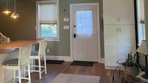 A spacious living area with a high ceiling fan, a kitchen with a dining table and chairs, a white door, and a large white cabinet. - Charming loft cottage in tranquil Germantown with WiFi, AC (Germantown)