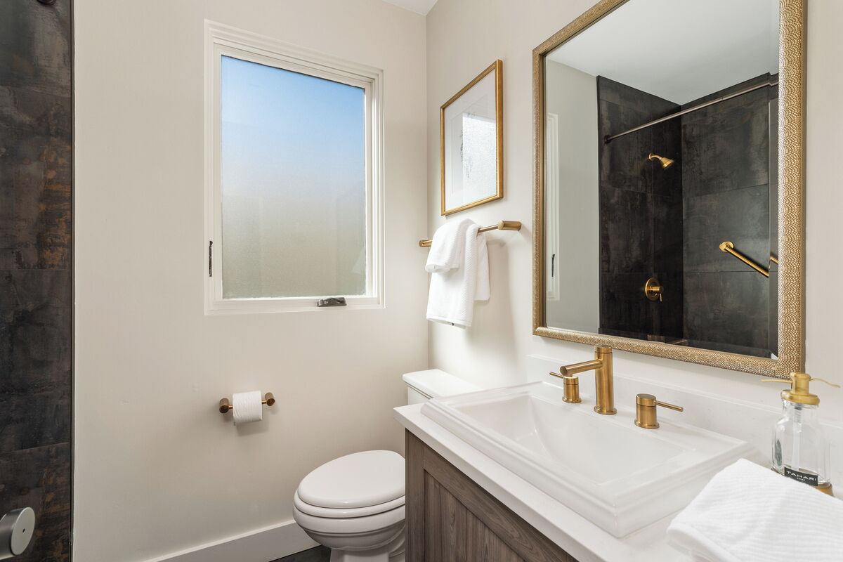 Een badkamer met een wit toilet, een grote spiegel en een bad.