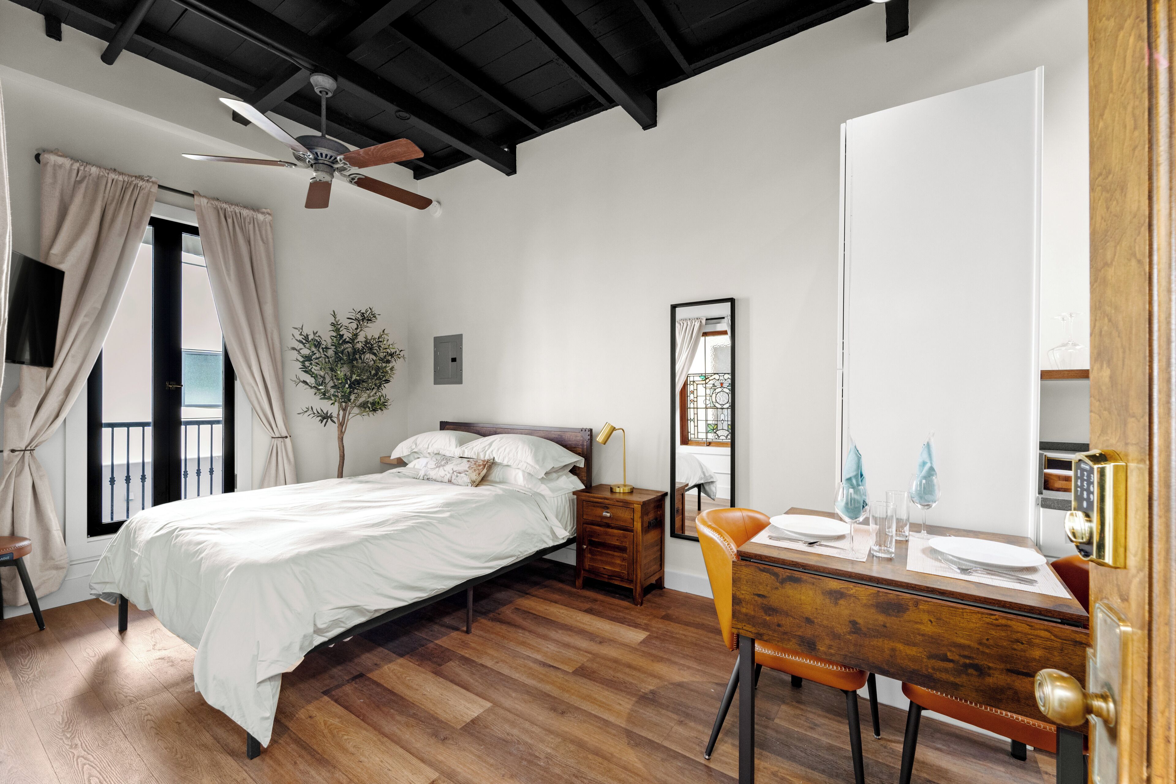 A bedroom with a bed, bedside table, chair, and a small desk with a mirror.