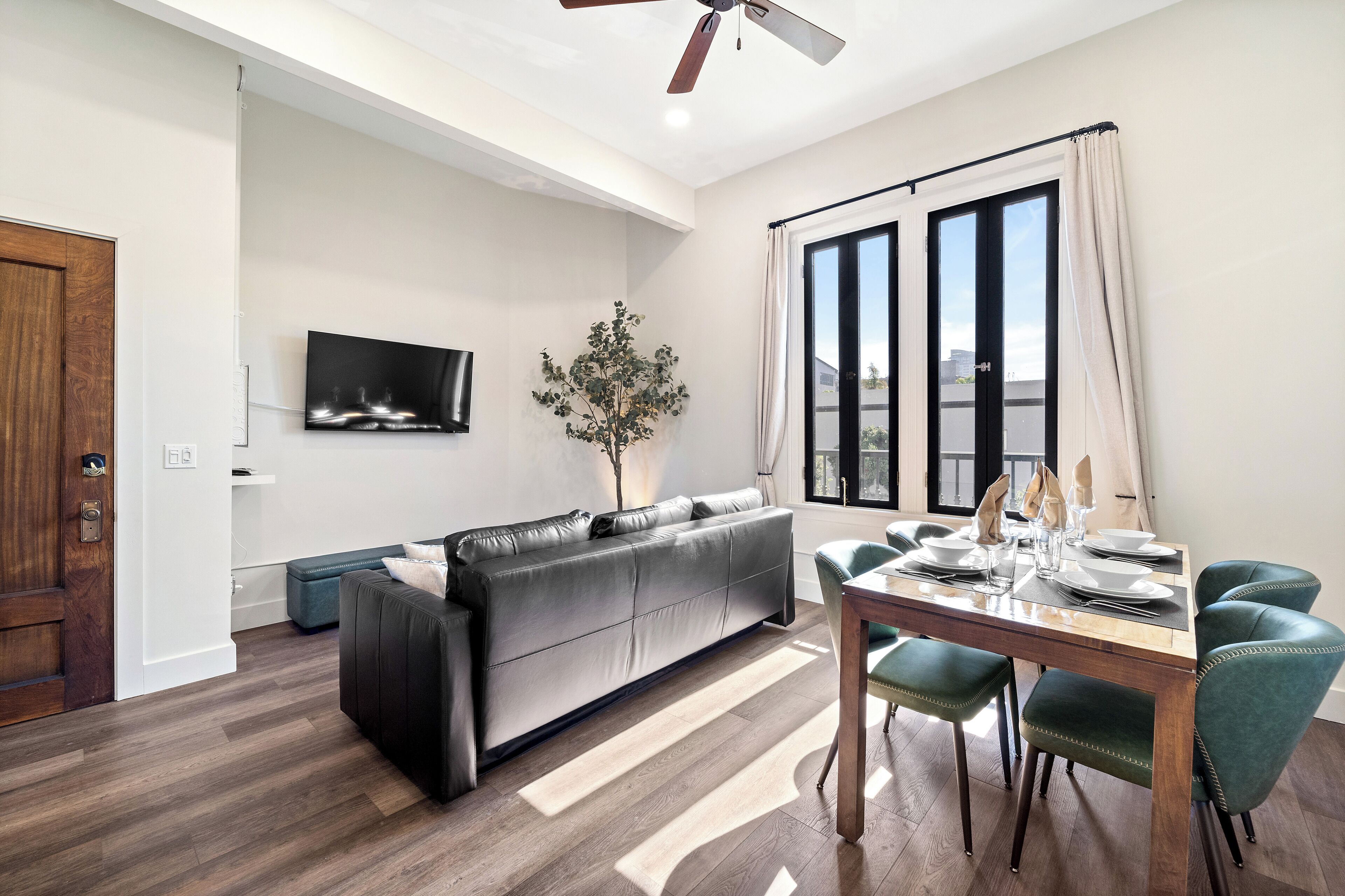 Un salon moderne comprenant un canapé, une table à manger, des chaises, un téléviseur et une plante.
