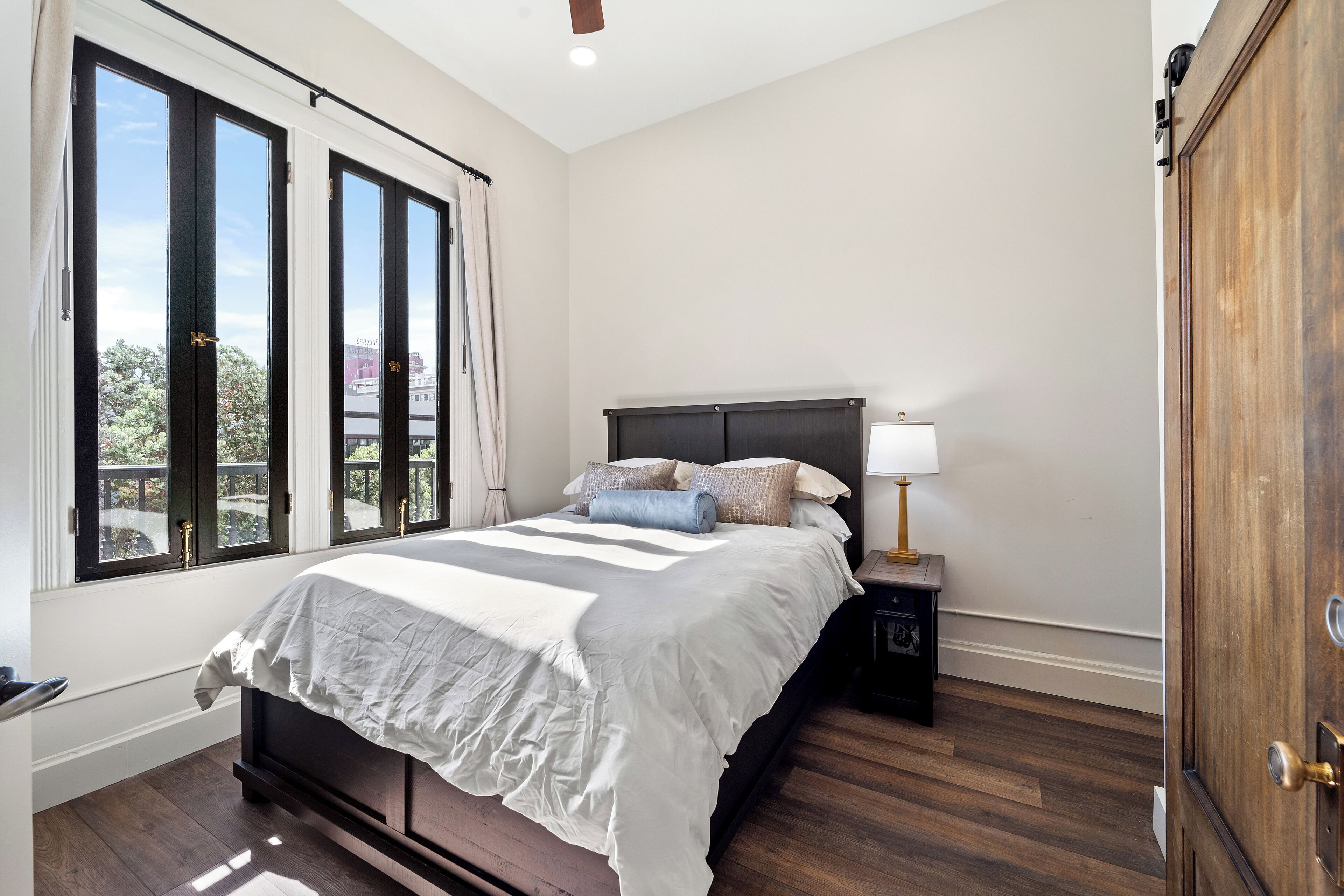 A bedroom with a large bed, a nightstand with a lamp, and a wardrobe.