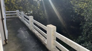 Eine Brücke mit weißen Geländern und einem Betonweg, umgeben von dichtem Grün.