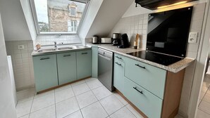 Una cucina compatta con finestra, fornello e lavastoviglie.