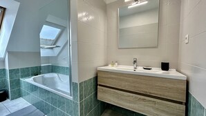 Un bagno moderno con doccia vetrata, una vasca freestanding e un mobile lavabo con specchio.