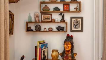 Een kamer met een hertenkop aan de wand, een houten kast met diverse voorwerpen, en een plank met decoratieve objecten.