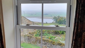 A window with a view of a stone wall and garden. - Lonin Cottage. Unwind in our cozy cottage, surrounded by scenic walks. (Barnard Castle)