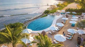 Ein Resort mit Swimmingpool, Liegestühlen am Strand und Sonnenschirmen.