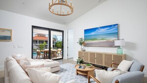 A spacious living room with a large window, a dining area, and a view of a pool and house.