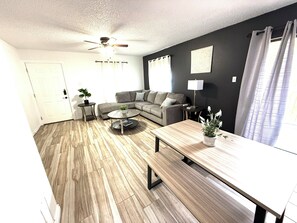 A modern living room with a grey sofa, a wooden coffee table, and a ceiling fan.