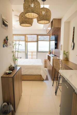 A compact hotel room with a bed, kitchenette, and a dining area with a bar. - Modern-Filipino Studio, short walk to Ever mall (Quezon City)