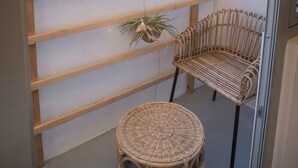 A balcony with a view of a cityscape, a wicker chair, and a small round table.