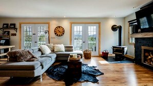 A living room with a grey sofa, a black leather rug, a wooden coffee table, and a fireplace. - YOMI Chalet - a peaceful oasis in the heart of nature (Lac-Supérieur)