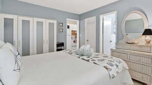 Ein Schlafzimmer mit Bett, Kommode, Spiegel und Kleiderschrank.