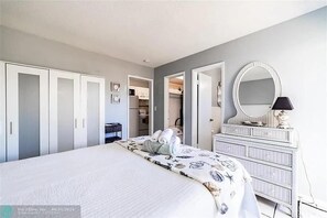 Quarto com cama, penteadeira, espelho e closet espaçoso.