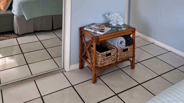 A room with a bed, a small table with a magazine, a wicker basket, and a poster on the wall. - BEACH OASIS - Walk 2 Beaches, Restaurants & Shops... Pets ok (Deerfield Beach)