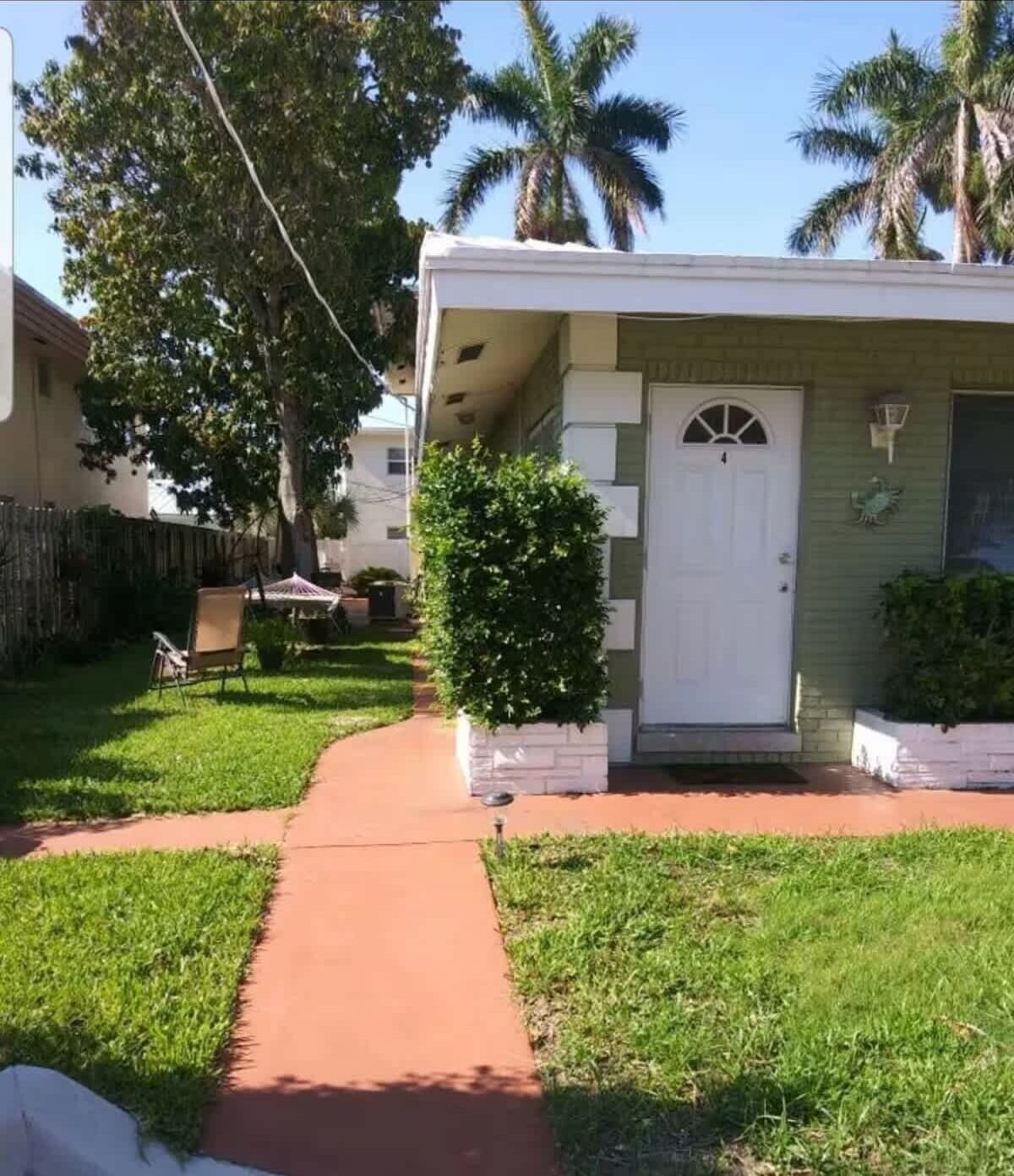 A single-story house with a front door, a small porch, and a pathway leading to the door.