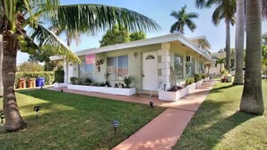 A two-story house with a front porch, a small garden, and palm trees. - BEACH OASIS - Walk 2 Beaches, Restaurants & Shops... Pets ok (Deerfield Beach)