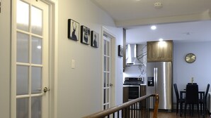 A staircase with a wooden handrail leading to a dining area with a table and chairs.