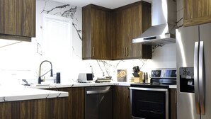 A modern kitchen with wooden cabinets, stainless steel appliances, and a marble backsplash.