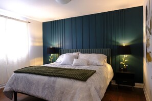 A bedroom with a bed, two bedside tables with lamps, a green rug, and a window with curtains. - Spacious 3-Bedroom Apartment|Perfect for Families (Mississauga)