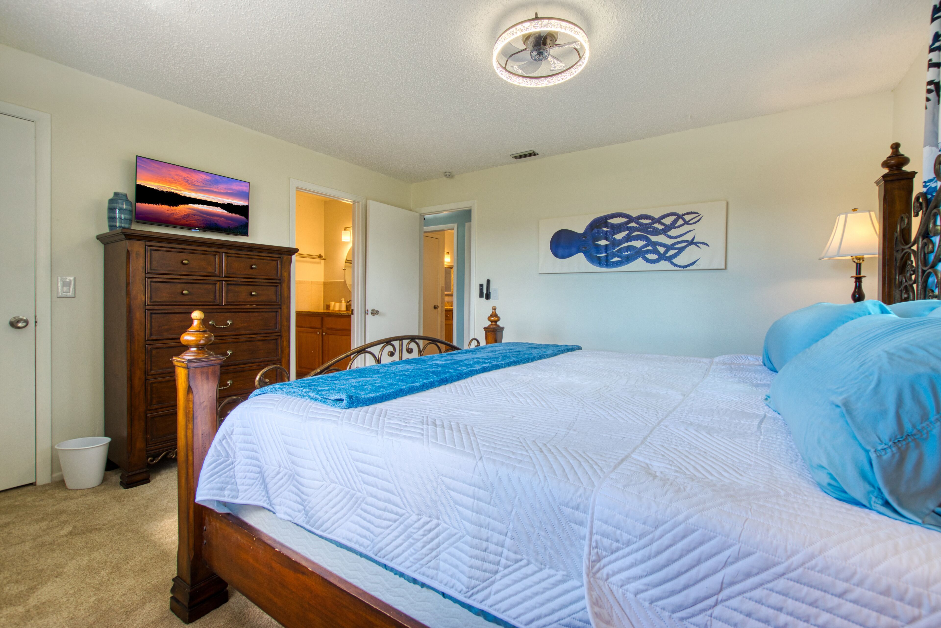 A bedroom with a bed, dresser, and artwork on the walls.