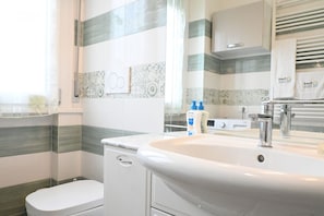 Un bagno con il water, un lavandino con specchio e piastrelle a righe sulle pareti.