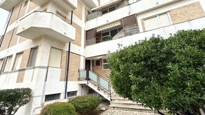 Un edificio residencial de varios pisos con balcones, una escalera y un jardín bien cuidado.