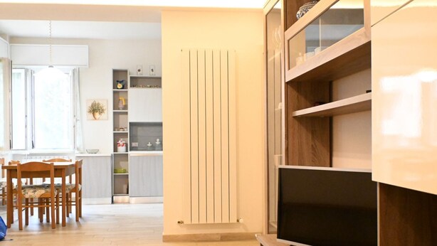 Una sala de estar moderna con un televisor de pantalla plana, muebles de madera y una cocina al fondo.