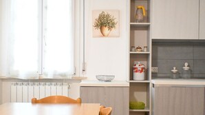 Una cocina moderna con una mesa de comedor, un radiador y un estante con utensilios de cocina.