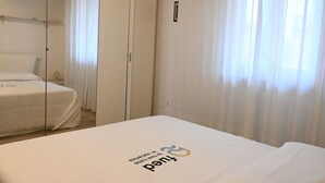 Una habitación de hotel con cama, armario y ventana con cortinas.