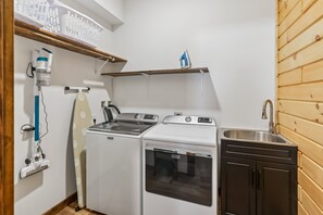 Une cuisine de taille réduite équipée d’un lave-linge, d’une cuisinière et d’un évier.