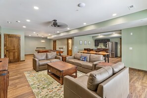A spacious living room with leather sofas, a pool table, and a dining area with wooden furniture.