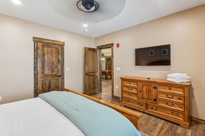 Une chambre à coucher avec un lit, une commode en bois et un téléviseur fixé au mur.