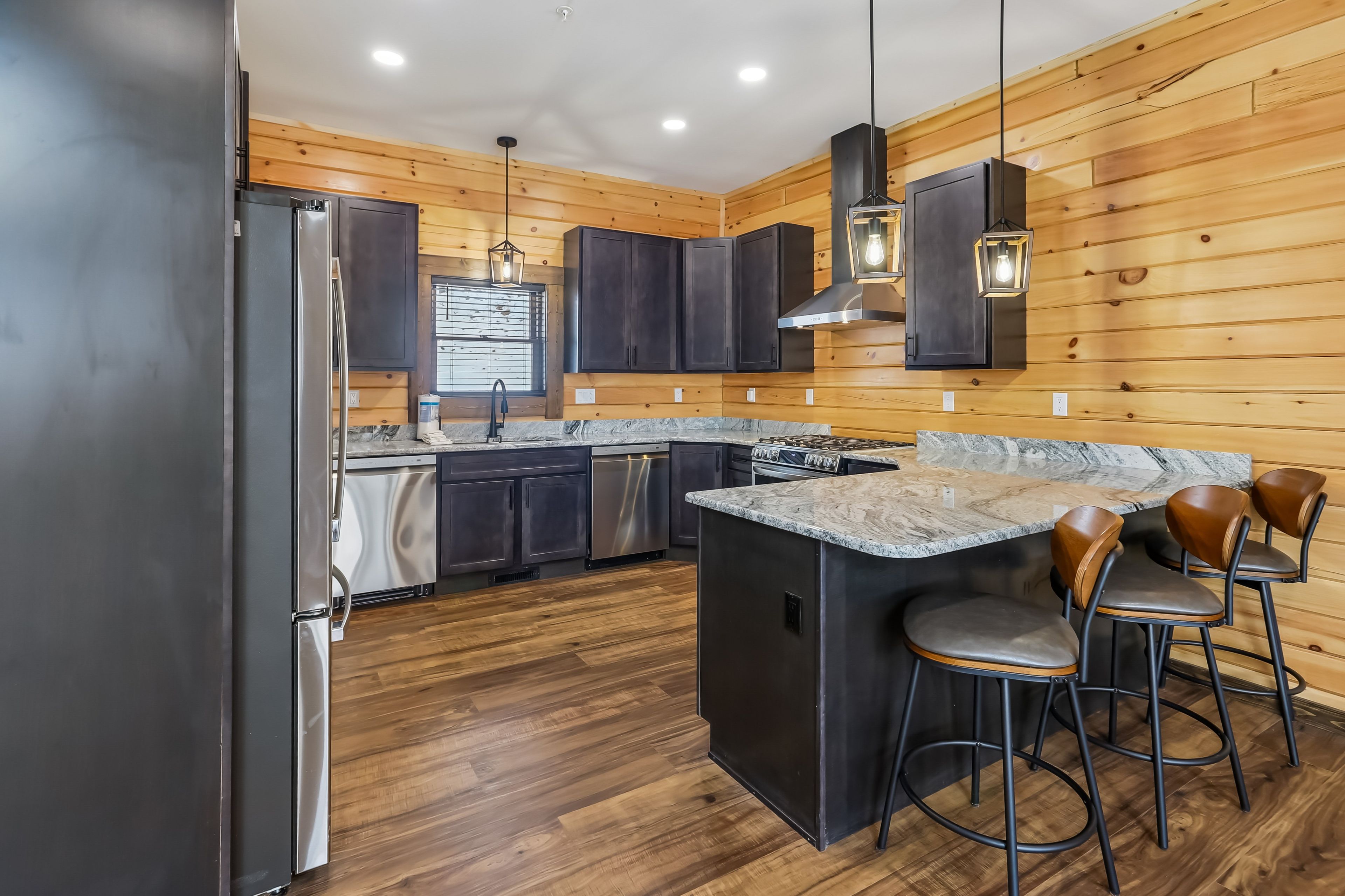A modern kitchen with wooden paneling, stainless steel appliances, and a marble countertop.