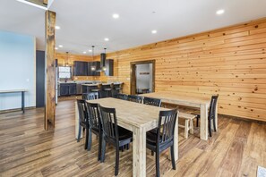 Une cuisine moderne avec un lambris en bois, un coin repas doté d’une grande table et de chaises, et une vue sur l’espace de vie adjacent.