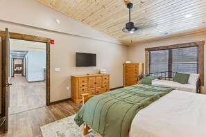 A bedroom with a bed, a dresser, a television, and a window with blinds.