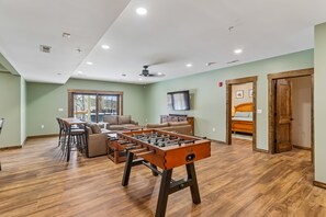 Un'ampia stanza con un tavolo da calcio, un divano e un'area pranzo con sedie.