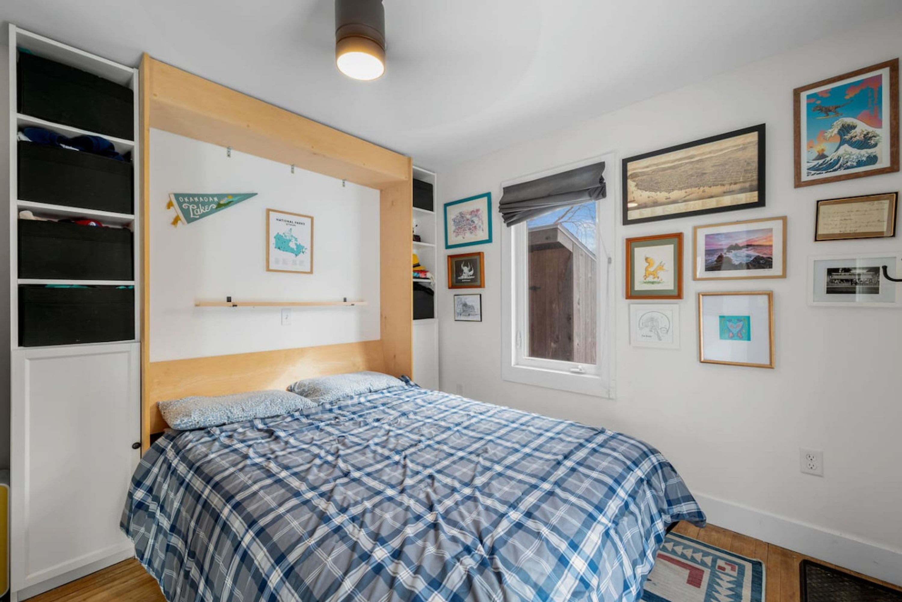 A bedroom with a bed, a wardrobe, and various framed pictures on the wall.