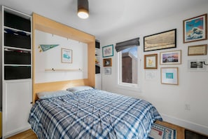 Quarto com cama, guarda-roupa e várias fotos emolduradas na parede.