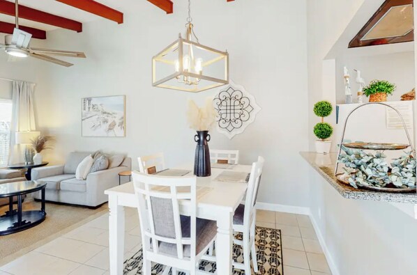 A modern dining area with a white table and chairs, a chandelier, and decorative wall art.