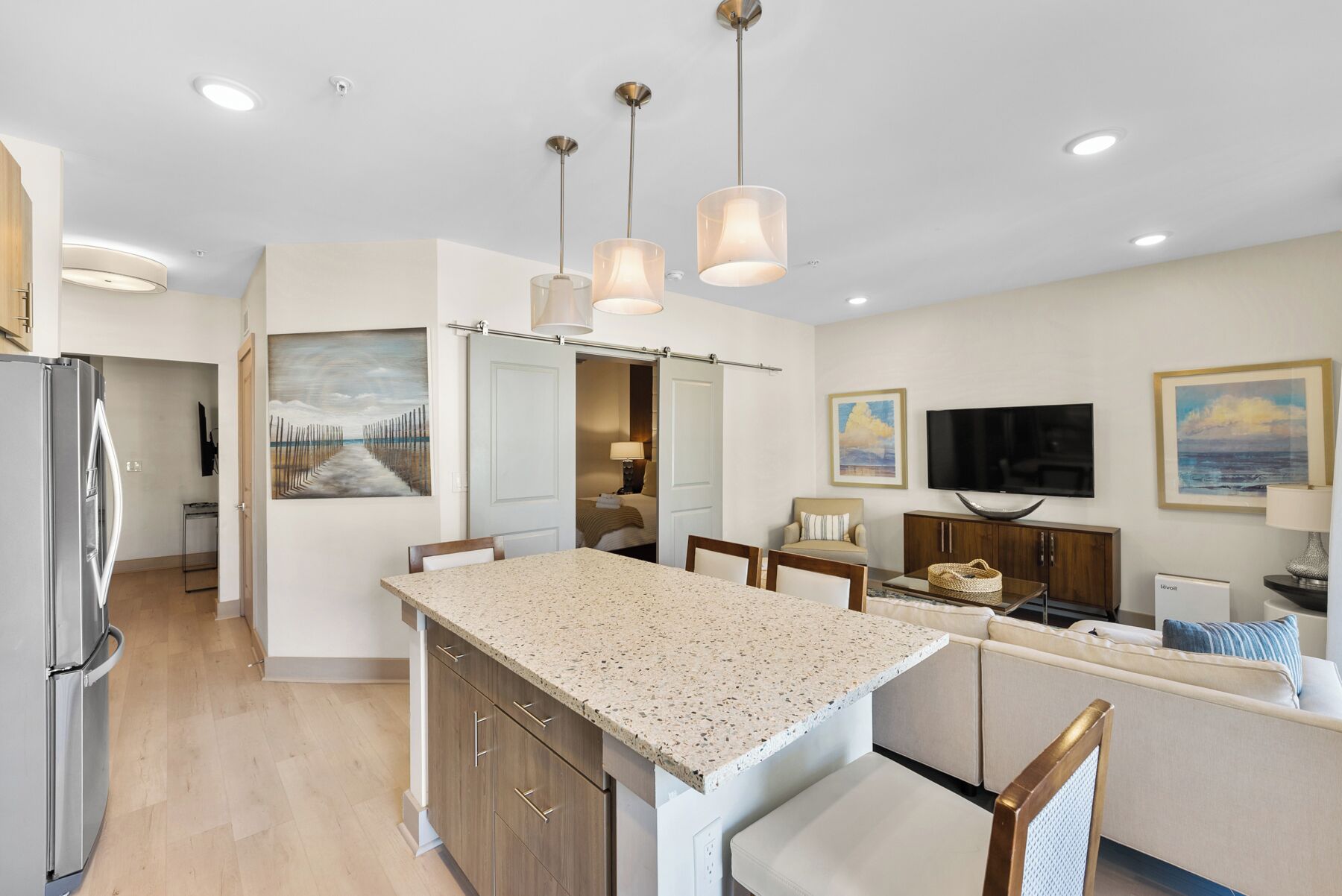 A modern kitchen with granite countertops, wooden cabinets, and pendant lighting.
