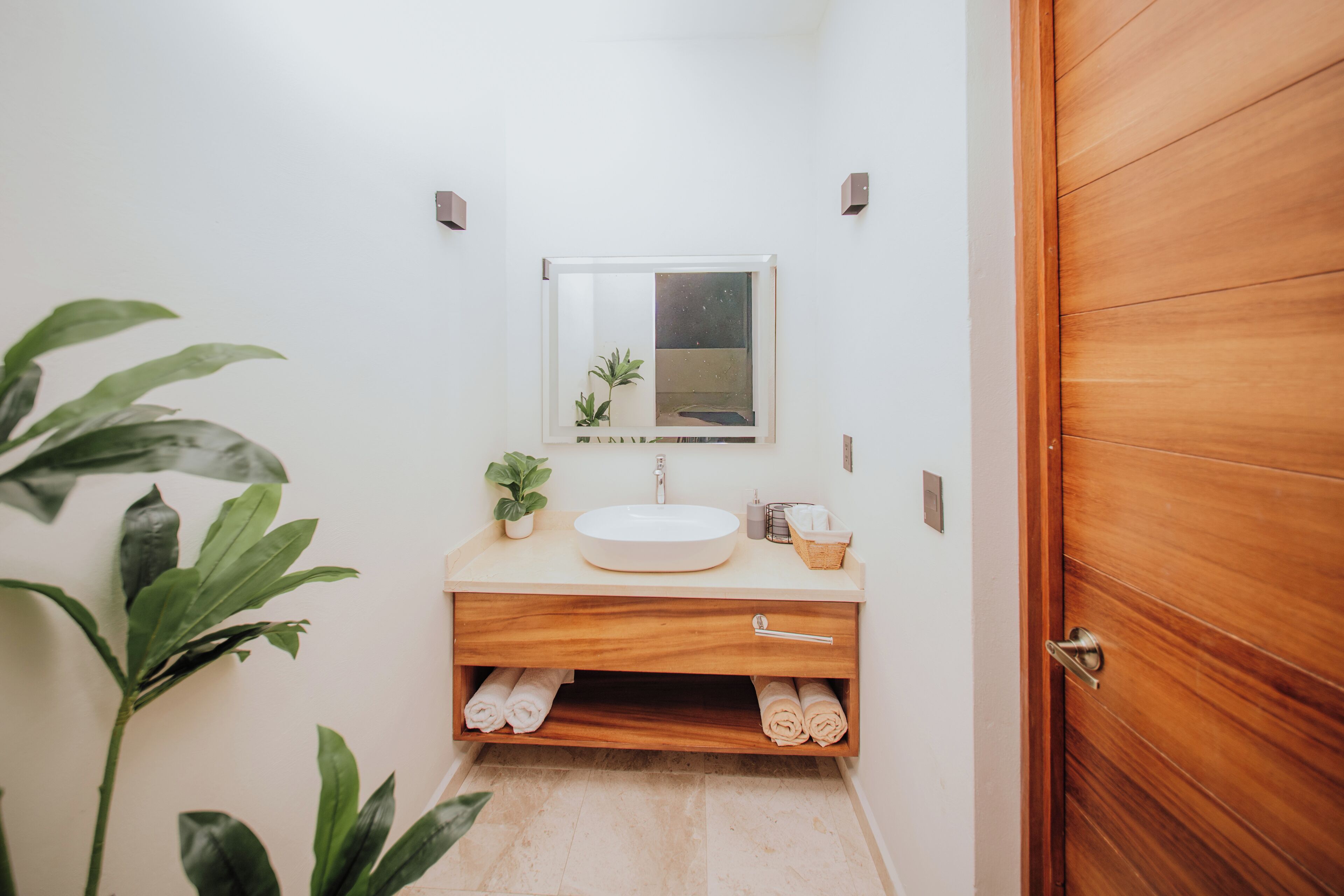 A bathroom with a wooden vanity, a sink, a mirror, and a towel rack.