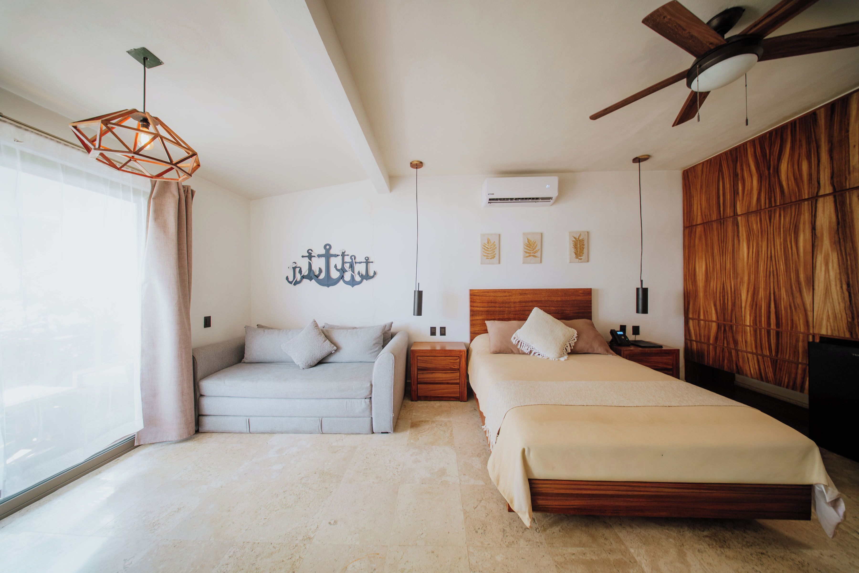 Une chambre à coucher avec un lit, un canapé, un ventilateur de plafond et une fenêtre.