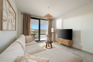 A modern bedroom with a large bed, a flat-screen TV, and a view of the outdoors. - Casa MLML | Pool - Terrace - Mountain Views (La Cala de Mijas)