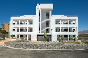 A modern two-story building with a central staircase, balconies, and a stone retaining wall. - Casa MLML | Pool - Terrace - Mountain Views (La Cala de Mijas)