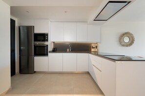 A modern kitchen with white cabinetry, a stainless steel refrigerator, a built-in oven, and a microwave. - Casa MLML | Pool - Terrace - Mountain Views (La Cala de Mijas)