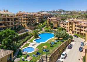 A resort with a large swimming pool surrounded by lush greenery and multiple buildings with balconies. - Casa MLML | Apartment with Mountain View in Mijas (La Cala de Mijas)