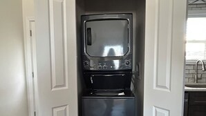 A compact kitchen with a built-in microwave and oven, white cabinetry, and a window above the sink.
