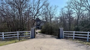 A gated driveway leading to a house with a dark roof and a visible garage.