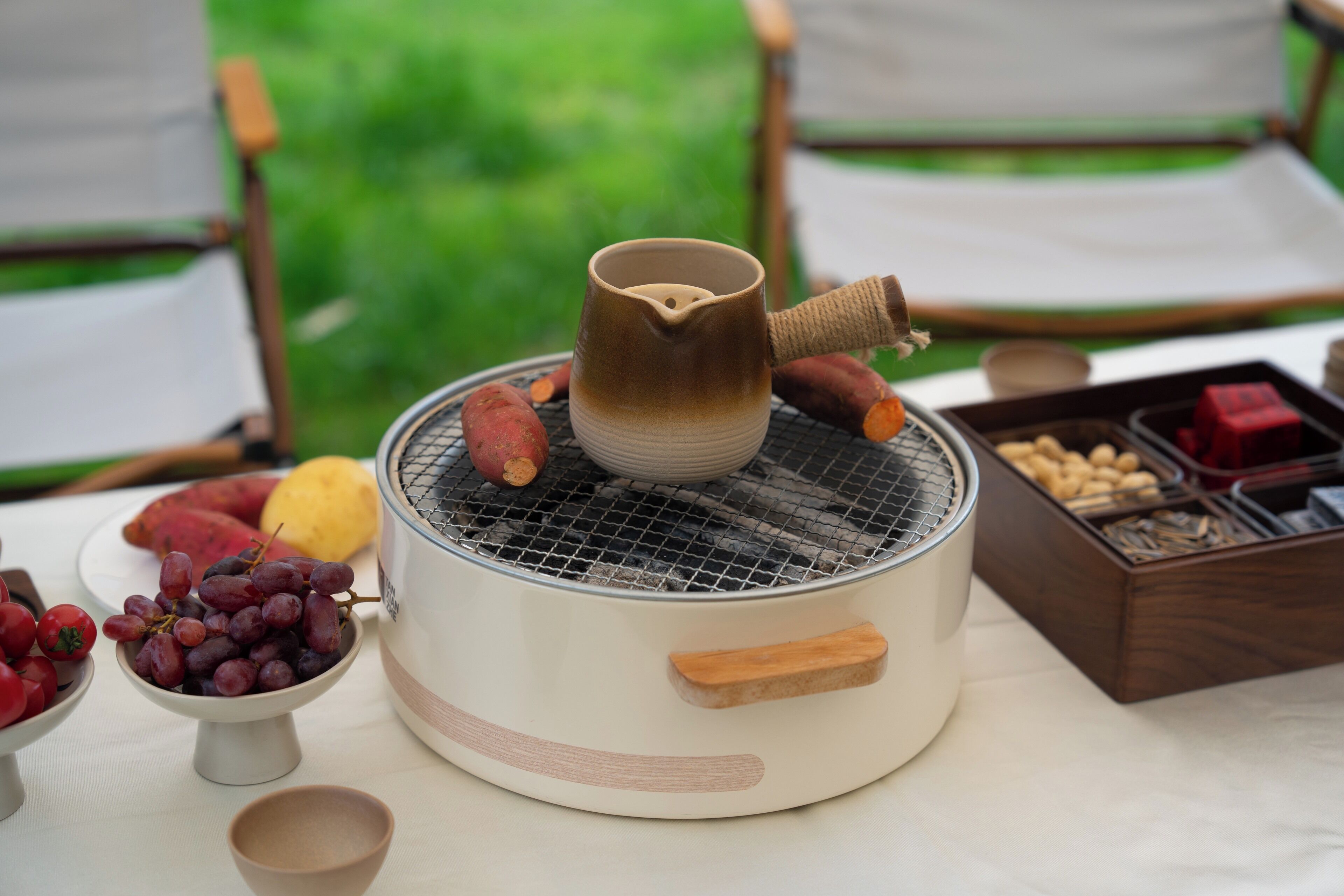 A portable stove with a pot on top, surrounded by various food items and containers.